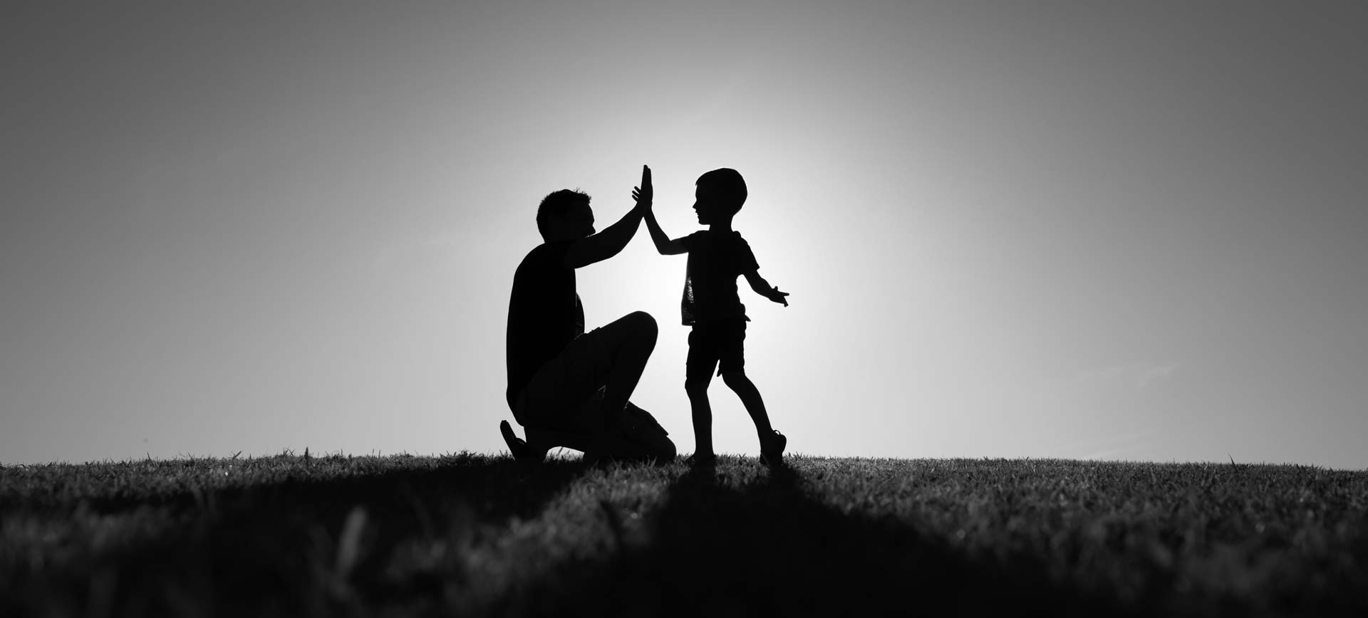 Silhouette of a man high fiving a child
