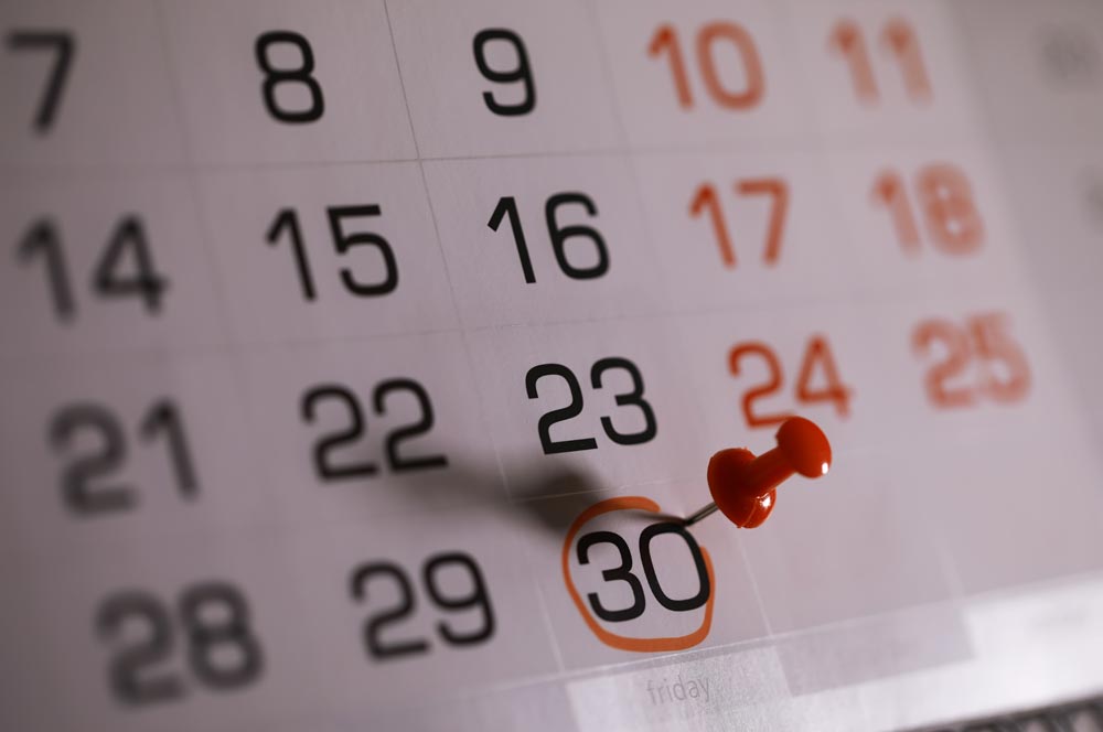 Close up of a calendar with the 30th day circled and marked with a pin